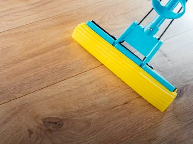 در حال نظافت پارکت ها با استفاده از یک طی مسطح زرد رنگ